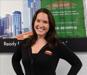 Servpro of Middletown shares picture of one of their project managers smiling and standing in front of a SERVPRO Ad picture. 